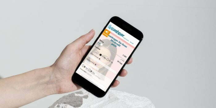 Hand hält Smartphone mit Finanz-App Cashper.
